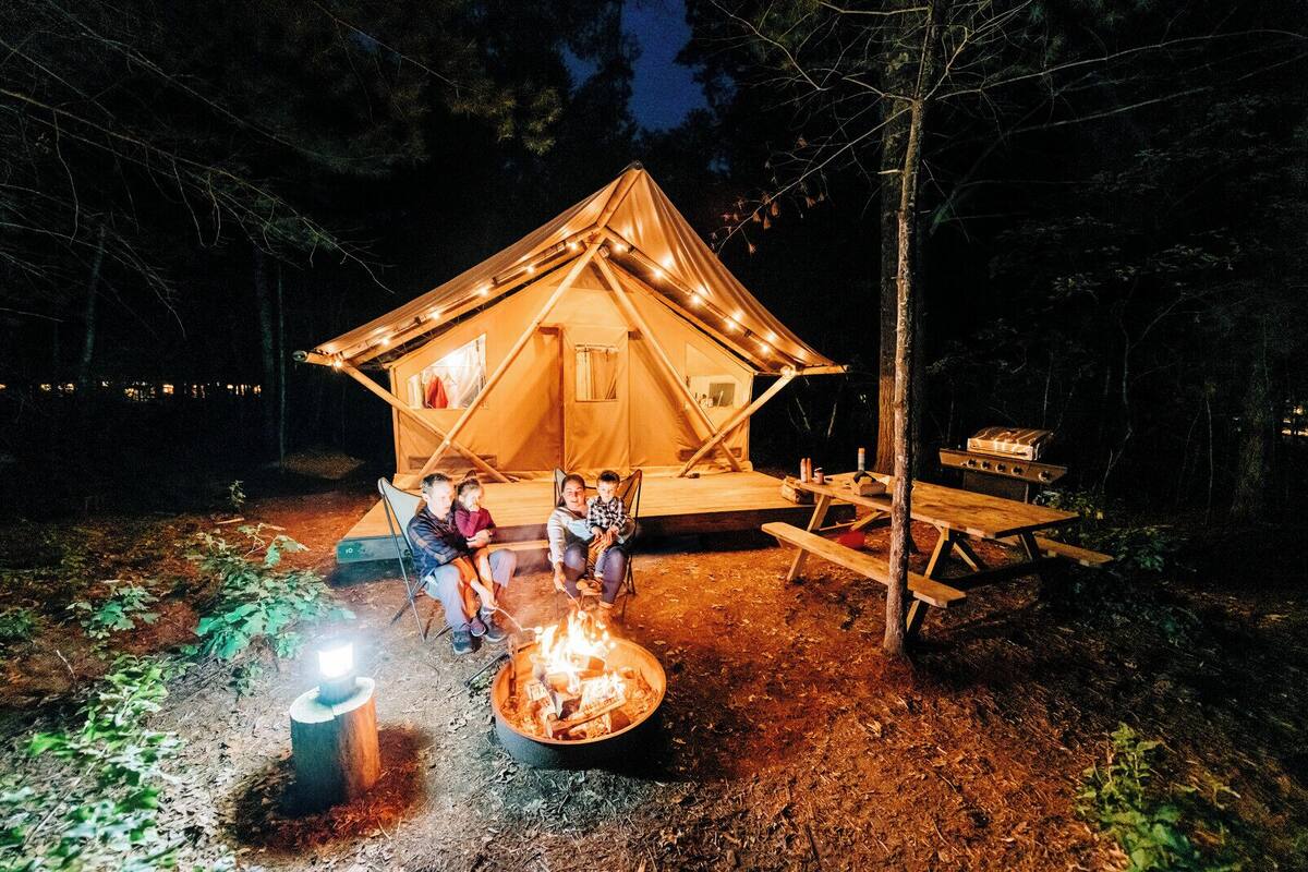 Une tente avec un foyer et une table de pique-nique, installées dans une forêt.