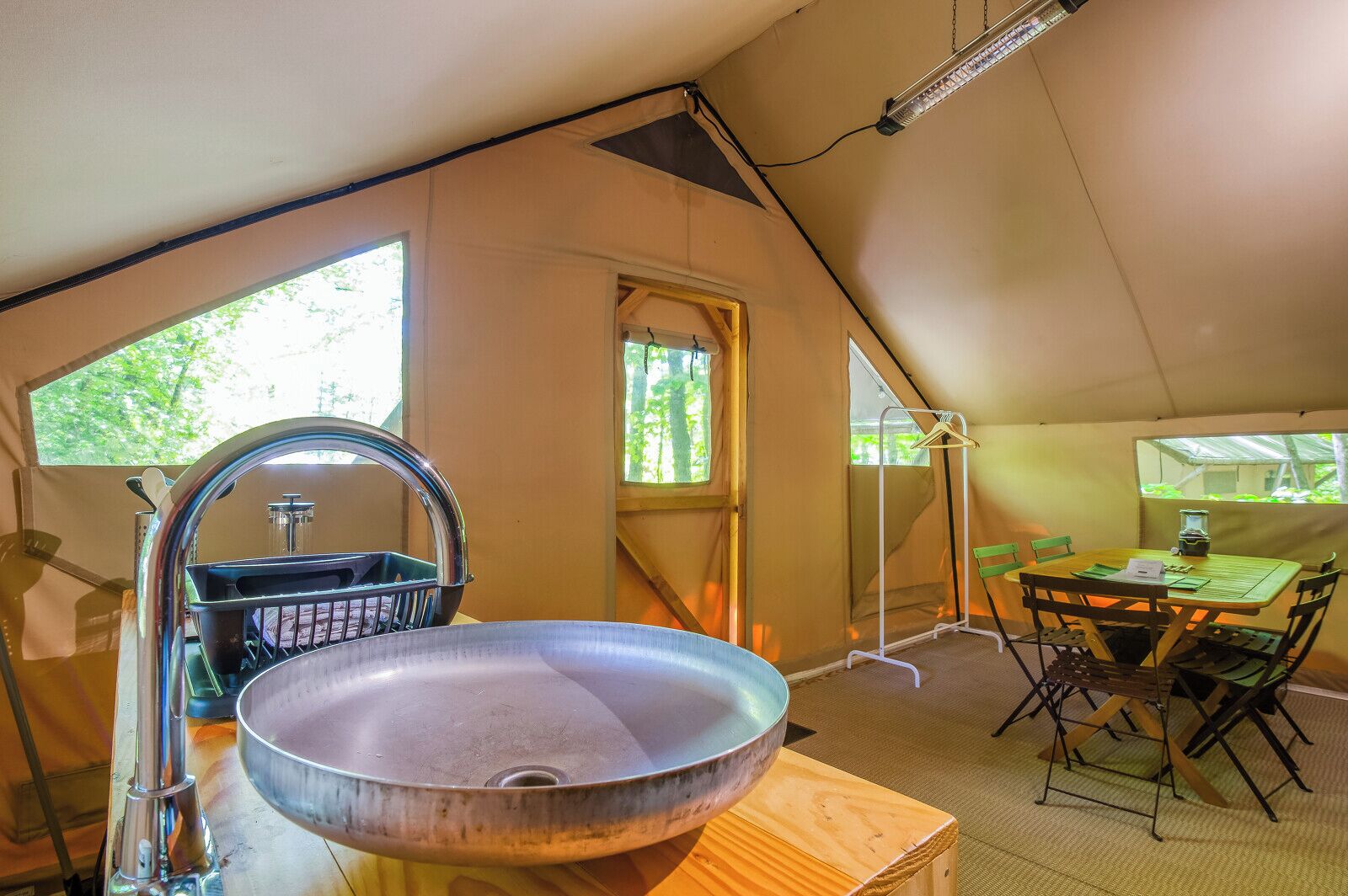 A compact kitchen with a sink, a window, and a dining area with a table and chairs.