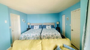 A bedroom with two beds, a yellow sofa, and a white door. - Easy Breezy Too! (Bonita Springs)