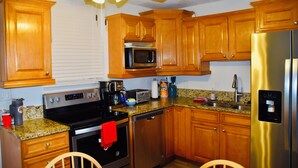 A kitchen with wooden cabinets, stainless steel appliances, granite countertops, and a ceiling fan. - Easy Breezy Too! (Bonita Springs)