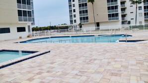 A swimming pool area with multiple pools, a tiled deck, and a white fence. - Easy Breezy Too! (Bonita Springs)