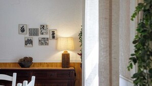 A dining area with a wooden table and chairs, a wall-mounted lamp, and framed artwork. - Casa Marmeleiro (Santiago do Cacém)