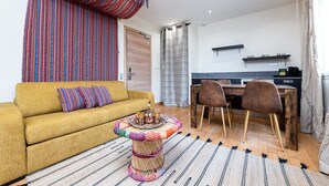A living room with a yellow sofa, a coffee table with a tray of cups, and a striped rug. - Apartment La Caravane du Touareg, Mandara Beach (Antibes)
