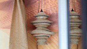 A textured, striped wall hanging with a wooden base, possibly a decorative piece or artwork.