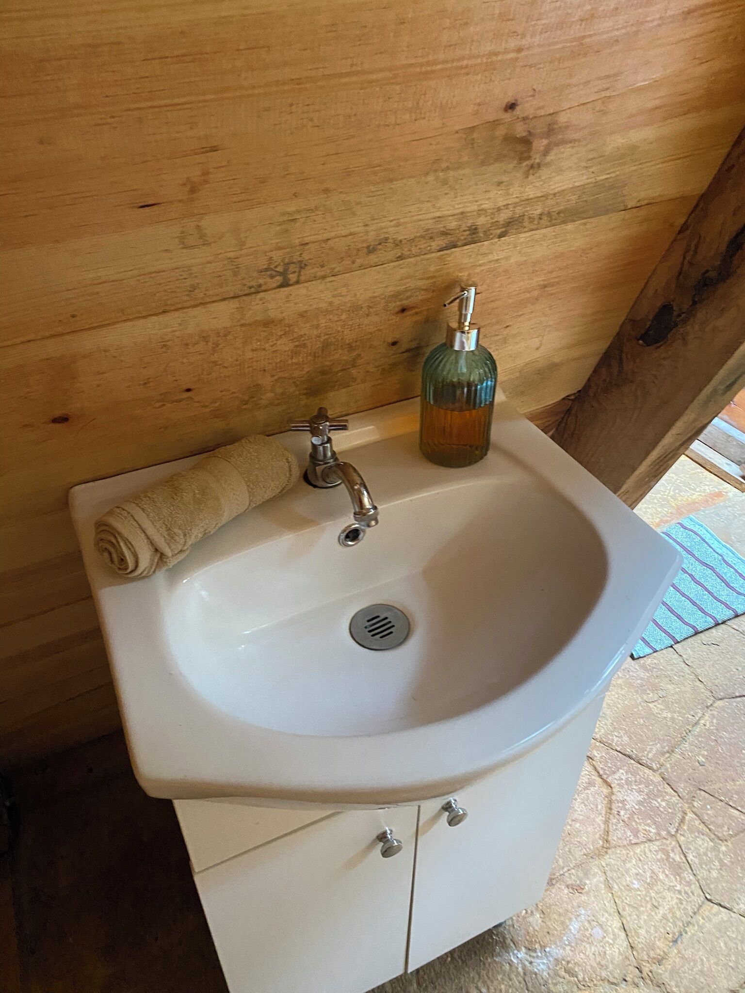 A white bathroom sink with a soap dispenser and a towel.