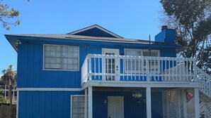 Una casa de dos pisos con fachada azul y balcón blanco.
