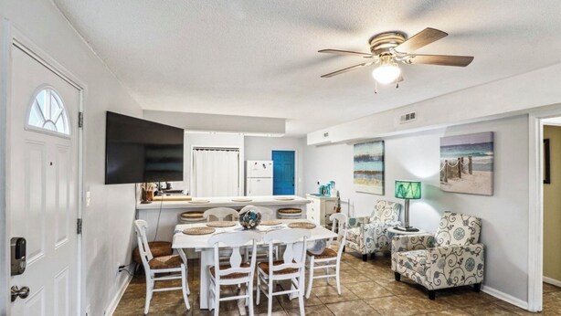 Un espacio habitable compacto con comedor, kitchenette y zona de estar con sillas estampadas.