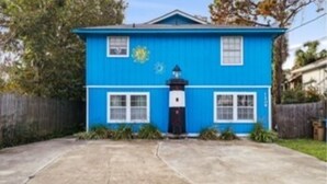 Una casa azul con un porche delantero, dos ventanas y una puerta.