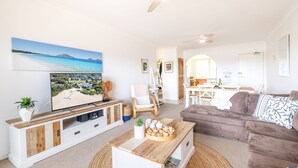 A living room with a TV, a sofa, a coffee table, and a dining area with a table and chairs.