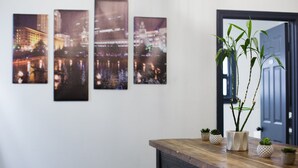 A room with a wooden table, a potted plant, and four framed cityscape photographs on the wall.