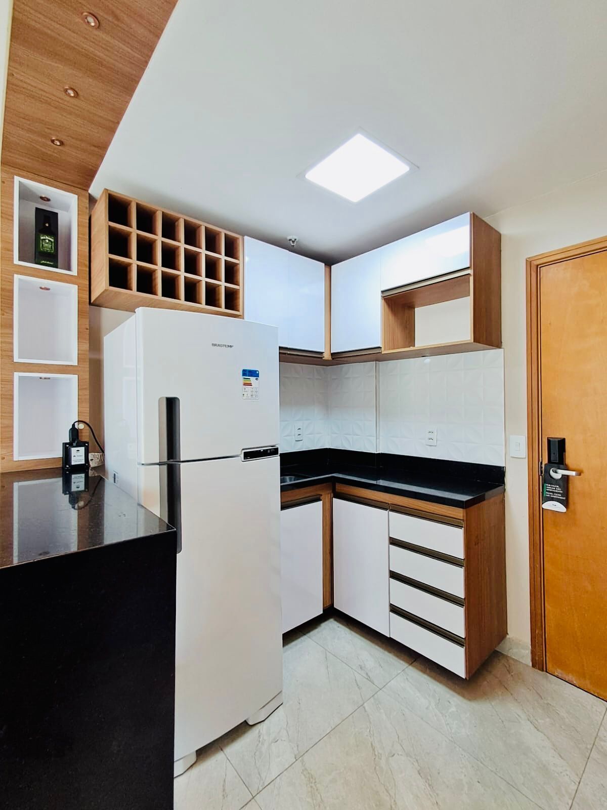 Una cocina moderna con refrigerador integrado, armarios de madera y encimera negra.