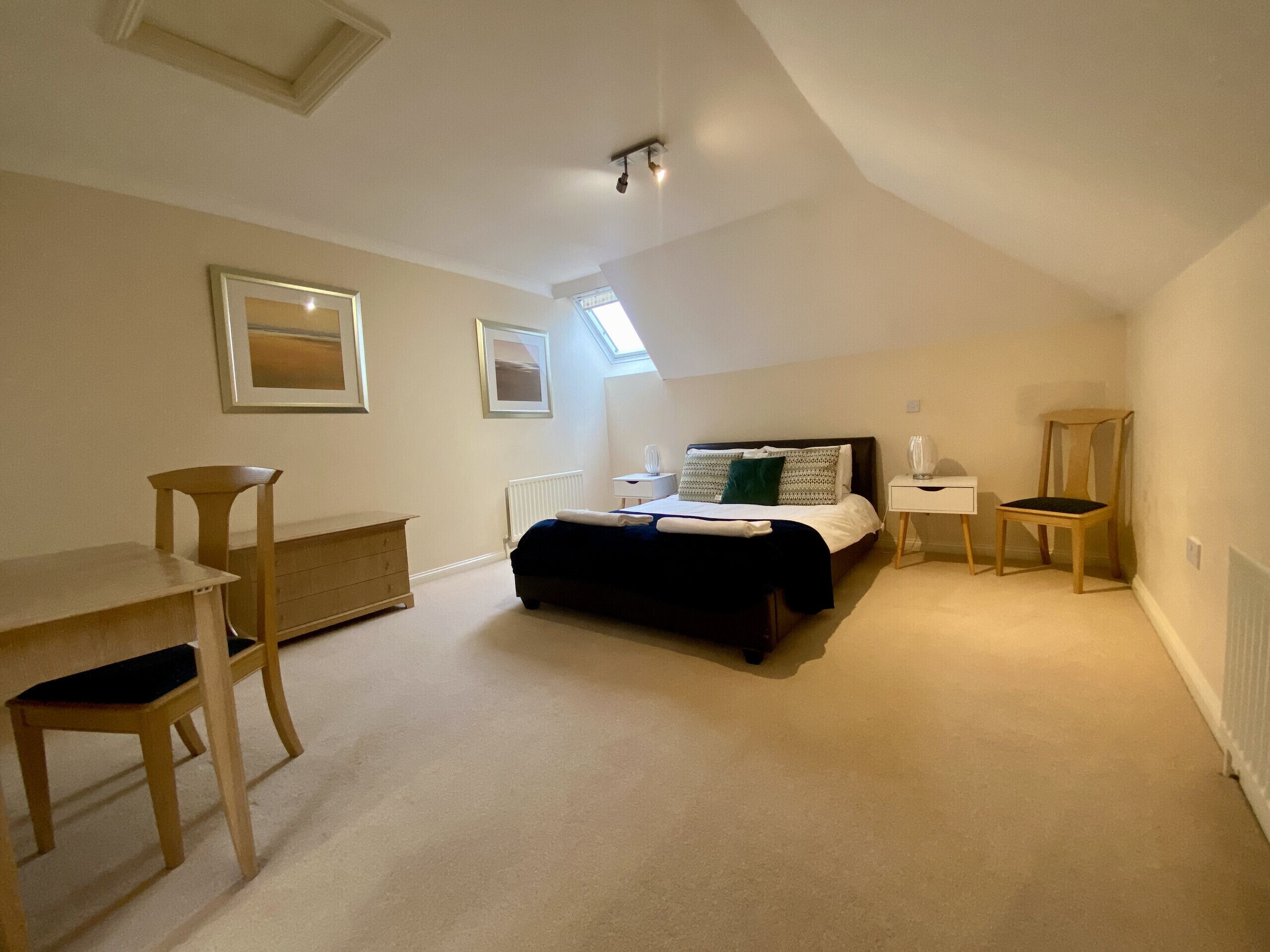 A bedroom with a bed, a desk, a chair, and a radiator.