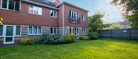 A two-story brick house with a well-maintained lawn and a wooden fence.
