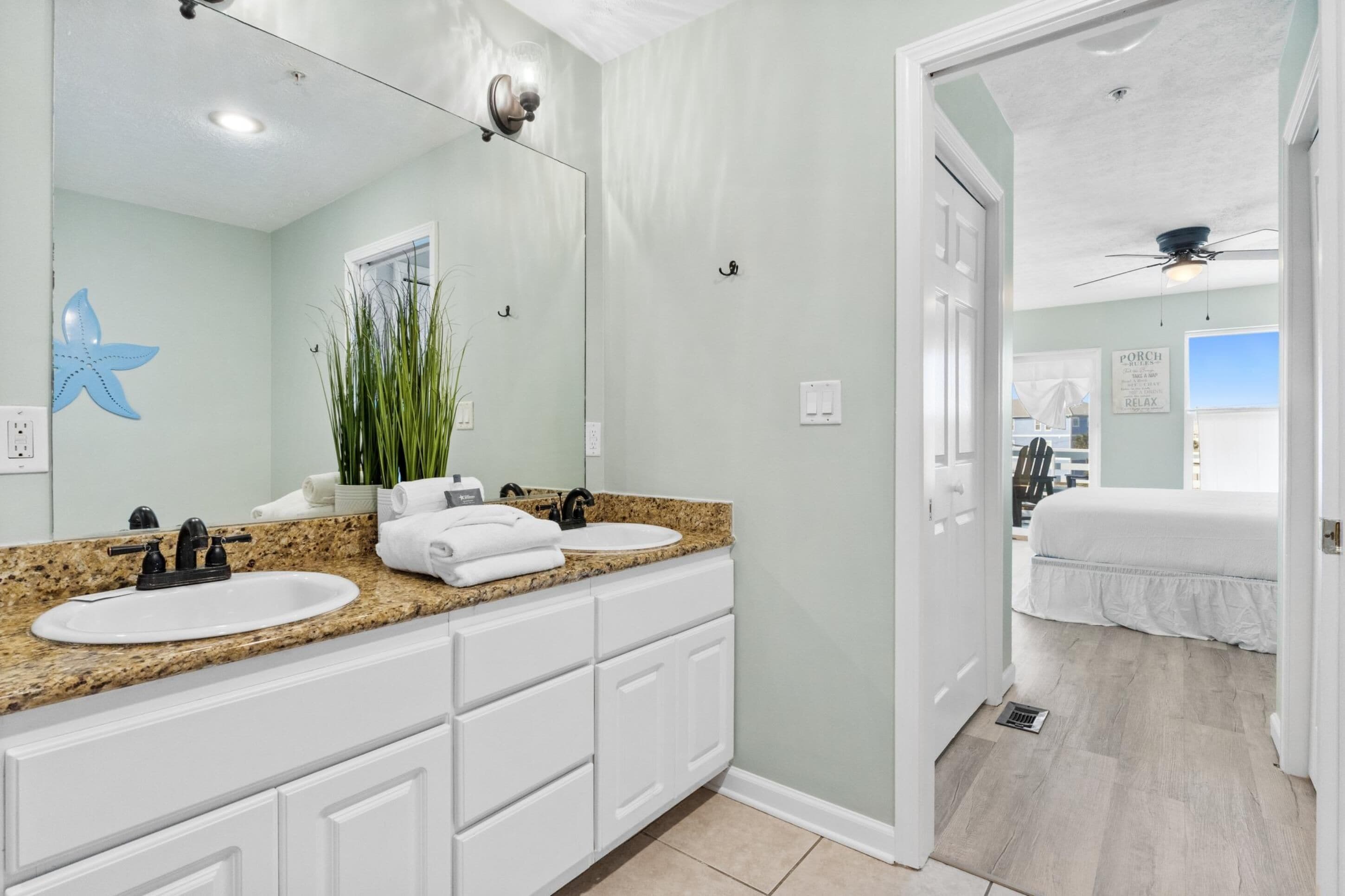 Un baño con dos lavamanos, un espejo grande y un ventilador de techo.