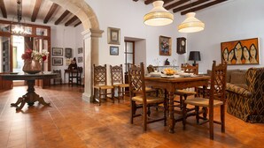 A dining area with a wooden table and chairs, a vase of flowers, and a painting on the wall.