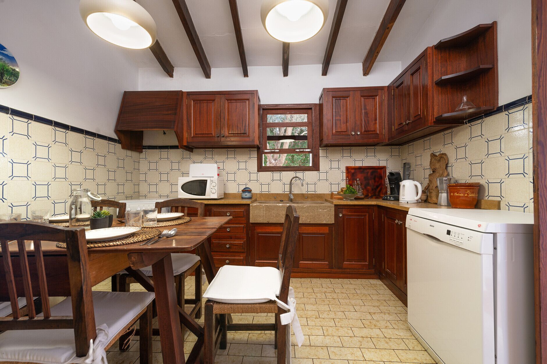 Een kleine keuken met houten kastjes, een magnetron, een spoelbak en een vaatwasser.