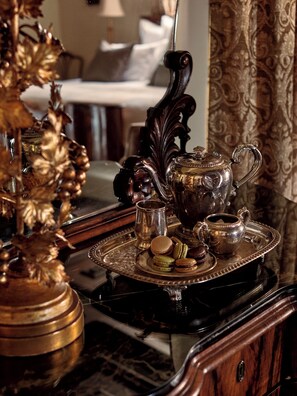 A luxurious setting with a vintage tea set on a tray, including a teapot, cups, and macarons, placed on a wooden table. - The Willows Palm Springs  (Palm Springs)