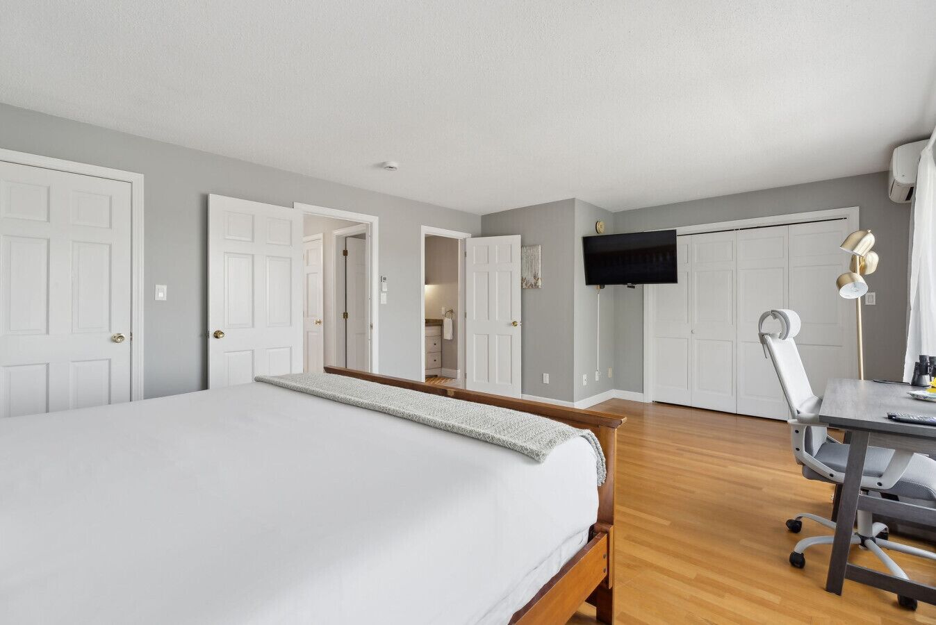 Une chambre d’hôtel avec un grand lit, un bureau avec une chaise, un téléviseur fixé au mur et une armoire.