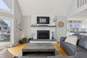 A modern living room with a fireplace, a flat-screen TV, and a cozy seating area. - Coastal Dream Vacation Home at Moody Beach - Sleeps 8 (Wells)