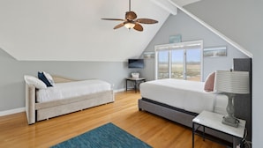 A bedroom with a sloped ceiling, a bed, a desk, a lamp, and a TV. - Coastal Dream Vacation Home at Moody Beach - Sleeps 8 (Wells)