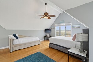 A bedroom with a sloped ceiling, a bed, a desk, a lamp, and a TV. - Coastal Dream Vacation Home at Moody Beach - Sleeps 8 (Wells)
