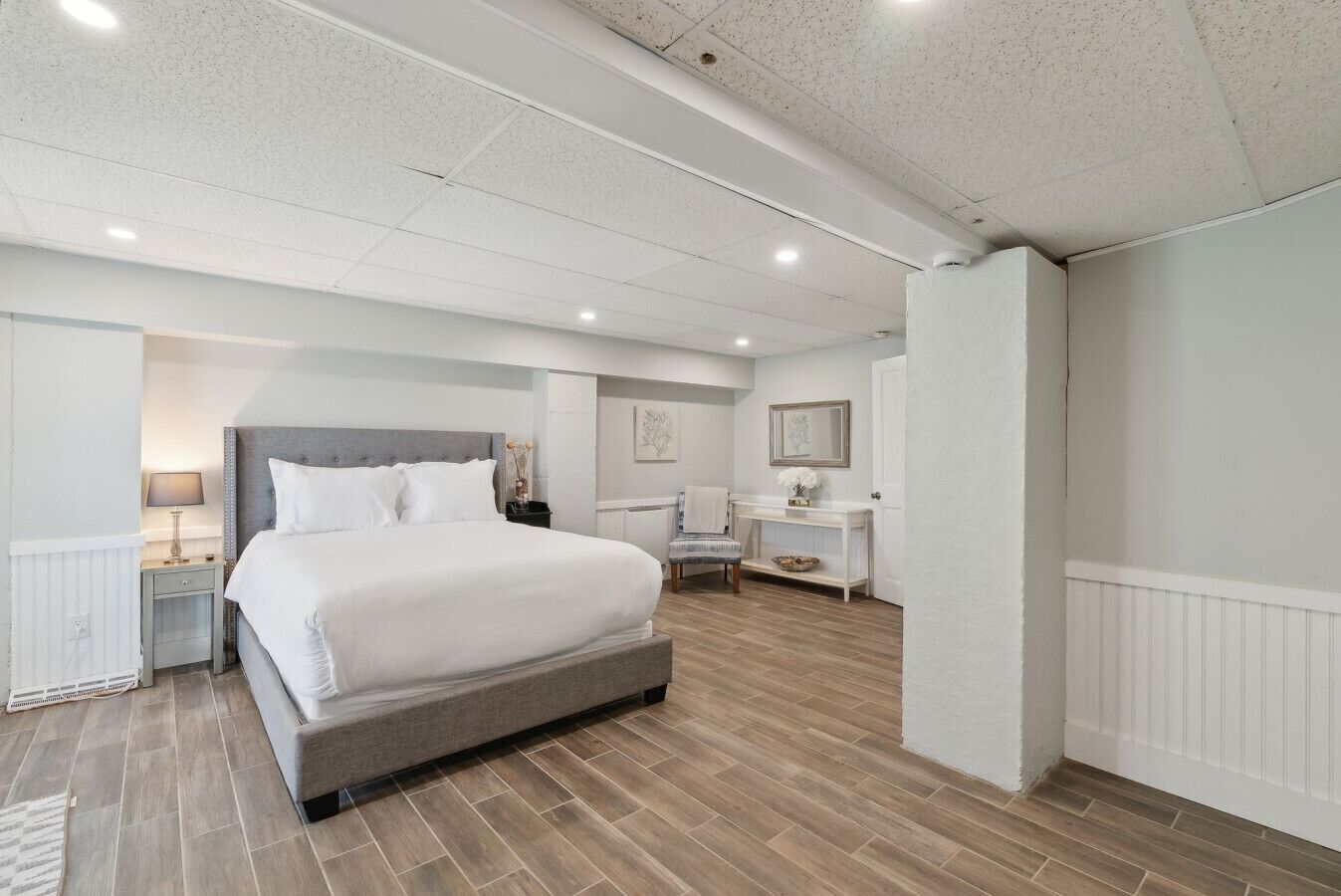 A modern bedroom with a large bed, bedside tables, a console table, and a chair.