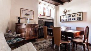 A dining area with a wooden table and chairs, a cushioned bench, a cabinet, and a wall with framed photos. - LA SUITE DEL CONVENTO (Potenza)