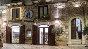 A stone building with a sign for a restaurant, wooden doors, and potted plants. - LA SUITE DEL CONVENTO (Potenza)