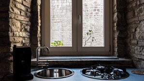 A kitchen with a window overlooking a stone building, a sink, and a stove. - LA SUITE DEL CONVENTO (Potenza)