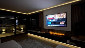 A modern living room with a flat-screen TV mounted on the wall, a fireplace, and a seating area with a rug. - Luxury Home in Granada with Private Pool (AN)
