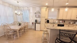 Una cocina moderna con una isla central, sillas de madera e iluminación colgante.