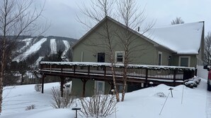 A house with a covered deck and a snow-covered landscape.