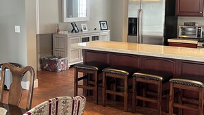 A modern kitchen with a central island, stainless steel appliances, and wooden bar stools.