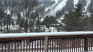 A snowy landscape with a wooden deck in the foreground.