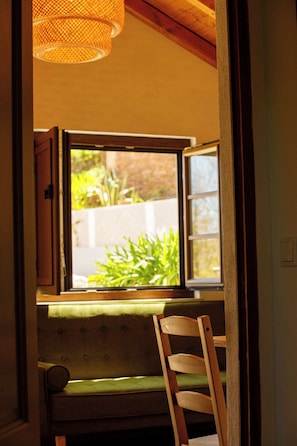 Une pièce avec une fenêtre, une chaise en bois et un banc vert avec un coussin.