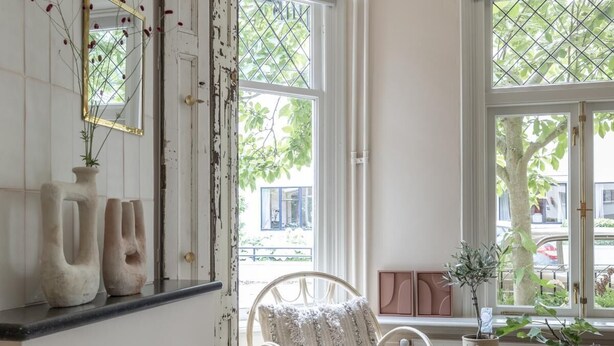 A spacious living room with a fireplace, a comfortable chair, a small table, and a large window providing a view of the outside. - Magnolia Tree - One Bedroom Apartment, Sleeps 2 (Bergen)