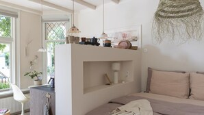 A bedroom with a bed, bedside table, hanging light, and a view of the outdoors. - Magnolia Tree - One Bedroom Apartment, Sleeps 2 (Bergen)