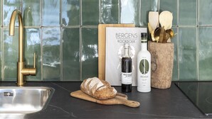 Een keuken met een houten aanrecht, een spoelbak, een hangende lamp en een plank met diverse keukenspullen.