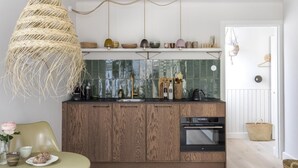 Een moderne keuken met houten kastjes, een inbouwoven en een hanglamp.