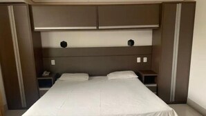 A hotel room with a large bed, two bedside tables, and a wardrobe.