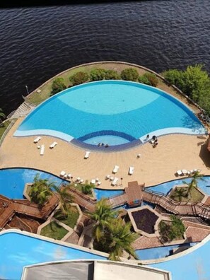 A large, circular swimming pool with a sandy beach area and lounge chairs. - Flat em Tropical Executive Hotel (Manaus)