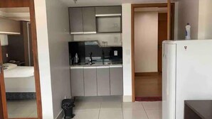 A compact hotel room with a kitchenette, a bed, and a small bathroom.
