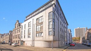 Ein Eckgebäude mit Backsteinfassade, großen Fenstern und einem flachen Dach.