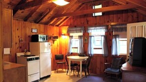 Una cocina compacta con refrigerador, microondas, estufa y comedor con mesa y sillas.