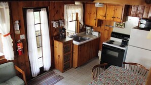 A compact kitchen with wooden cabinets, a sink, a stove, and a refrigerator. - Birch Cottage-Private Beach-Pets Welcome - Round Table Lodge, Sebago, Maine (Sebago)