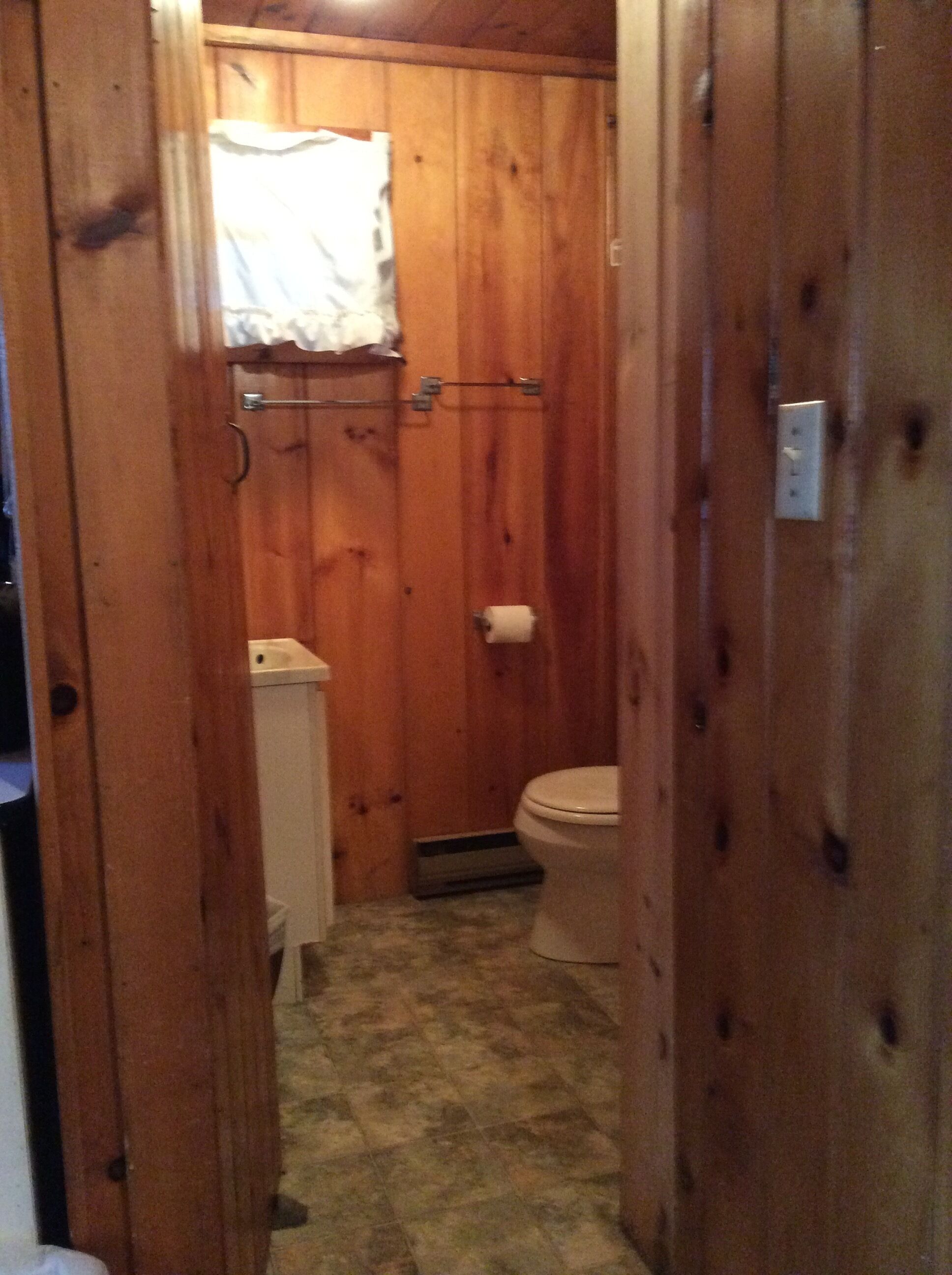 Een betegelde badkamer met toilet, een handdoekhouder en een douchegordijn.