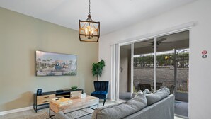 A living room with a sofa, coffee table, and a painting on the wall. - Condo 2bed 2bath Next to Disney w Free Water Park (Davenport)