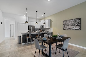A modern kitchen with white cabinets, a central island, and pendant lighting. - Condo 2bed 2bath Next to Disney w Free Water Park (Davenport)