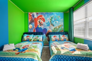 Une chambre avec deux lits, chacun agrémenté de draps et d’oreillers aux motifs de Mario.