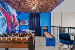 Une pièce équipée d’un baby-foot, d’une table de ping-pong et d’une fresque murale sur le thème de Spider-Man.